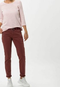 Pantalons cargo rouges avec poches latérales, assortis à une chemise rayée à manches trois-quarts. L'ensemble comprend des baskets blanches.