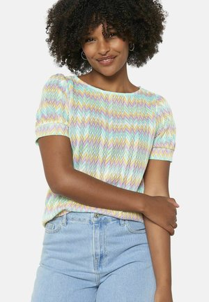 Patroon gebreide top met zigzagdesign in pasteltinten, ronde halslijn en korte puffmouwen. Gemaakt met lichtblauwe high-waisted jeans.