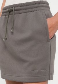 Γκρι αθλητικές βερμούδες με ελαστική μέση, κορδόνι, πλαϊνές τσέπες και κεντημένη λεπτομέρεια με λογότυπο στο τελείωμα. Ομαλή υφή.