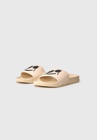 Beige slip-on sandals with a textured sole, featuring black palm tree designs on the top. Made from smooth synthetic material.