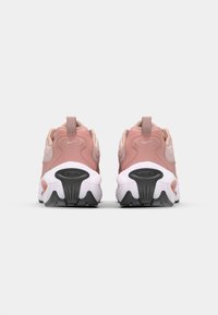 Les baskets présentent une tige rose avec des accents clairs, un dos texturé et une semelle intermédiaire blanche avec une semelle extérieure noire proéminente.