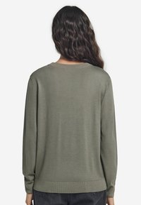 Olivgrüner Pullover in lockerer Passform, mit langen Ärmeln und rundem Ausschnitt. Weicher Stoff mit gerippten Bündchen und Saum.