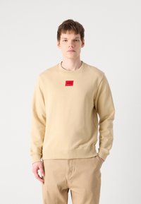Felpa beige in misto cotone con polsini e orlo ribbed. Presenta un'etichetta con logo rettangolare rossa sul petto.