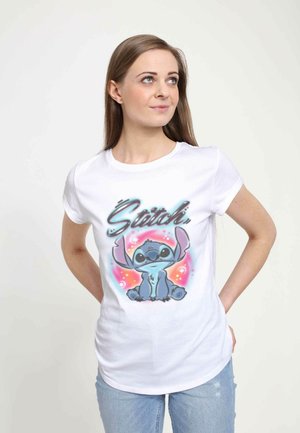 Hvid bomulds T-shirt med et farverigt grafik af en tegneseriefigur med store ører og teksten "Stitch" i kunstnerisk skrifttype.