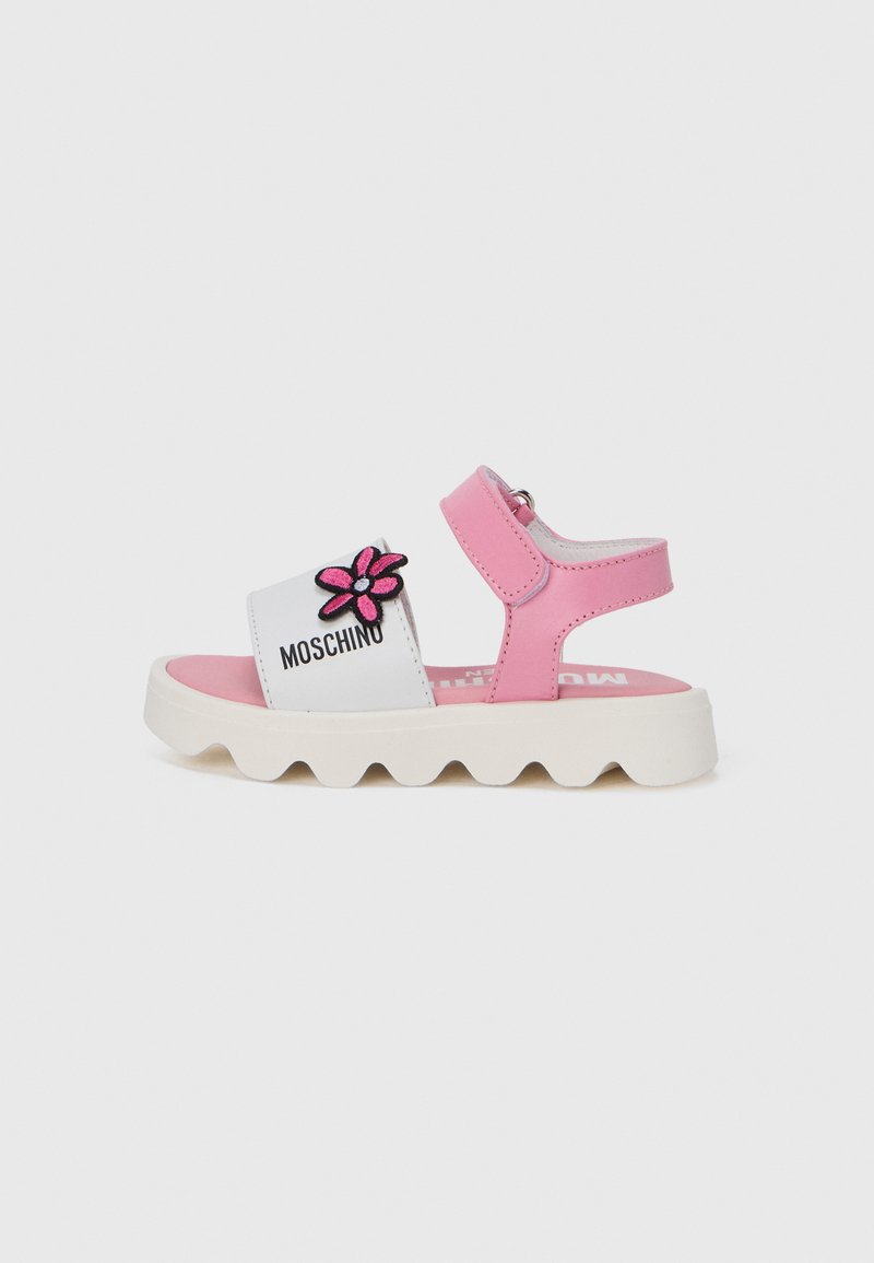 Sandales roses et blanches avec un appliqué floral, dotées d'une semelle en caoutchouc, d'une bride réglable et d'un bord ondulé pour une meilleure adhérence.