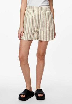 Pantaloni corti a righe beige e bianchi con vita elasticizzata e tasche laterali, realizzati in tessuto leggero, abbinati a sandali neri a infradito.