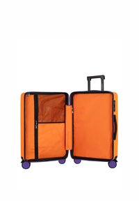 Walizka z twardą skorupą o pomarańczowej powierzchni zewnętrznej, czarnymi zamkami błyskawicznymi i fioletowymi kółkami. Wnętrze wyposażone w siatkowaną kieszeń i boczną przegrodę. Rączka teleskopowa.