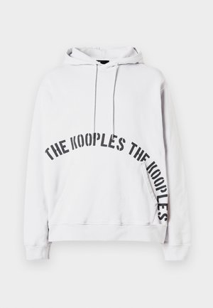 White hooded sweatshirt with front pocket and black text "THE KOOPLES" printed in a curved design across the front and side.