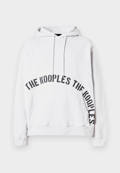 Weißer Kapuzenpullover mit Fronttasche und schwarzem Text "THE KOOPLES", der in einer gebogenen Schriftart über die Vorder- und Seitenfläche gedruckt ist.