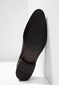 Semelle de chaussure en cuir noire, avec un motif texturé et nervuré pour une meilleure adhérence. Présente une taille estampée "42" et des bords lisses.