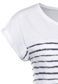 Balts T-krekls ar apaļu kakla izgriezumu un īsām, rullētām piedurknēm. Iezīmējas ar tumši zila krāsas horizontālām svītrām. Mīksta tekstūra un ikdienišķs dizains.