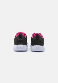 Zapatillas deportivas negras con una suela blanca texturizada y detalles en rosa, que cuentan con una lengüeta y un diseño superior transpirable.