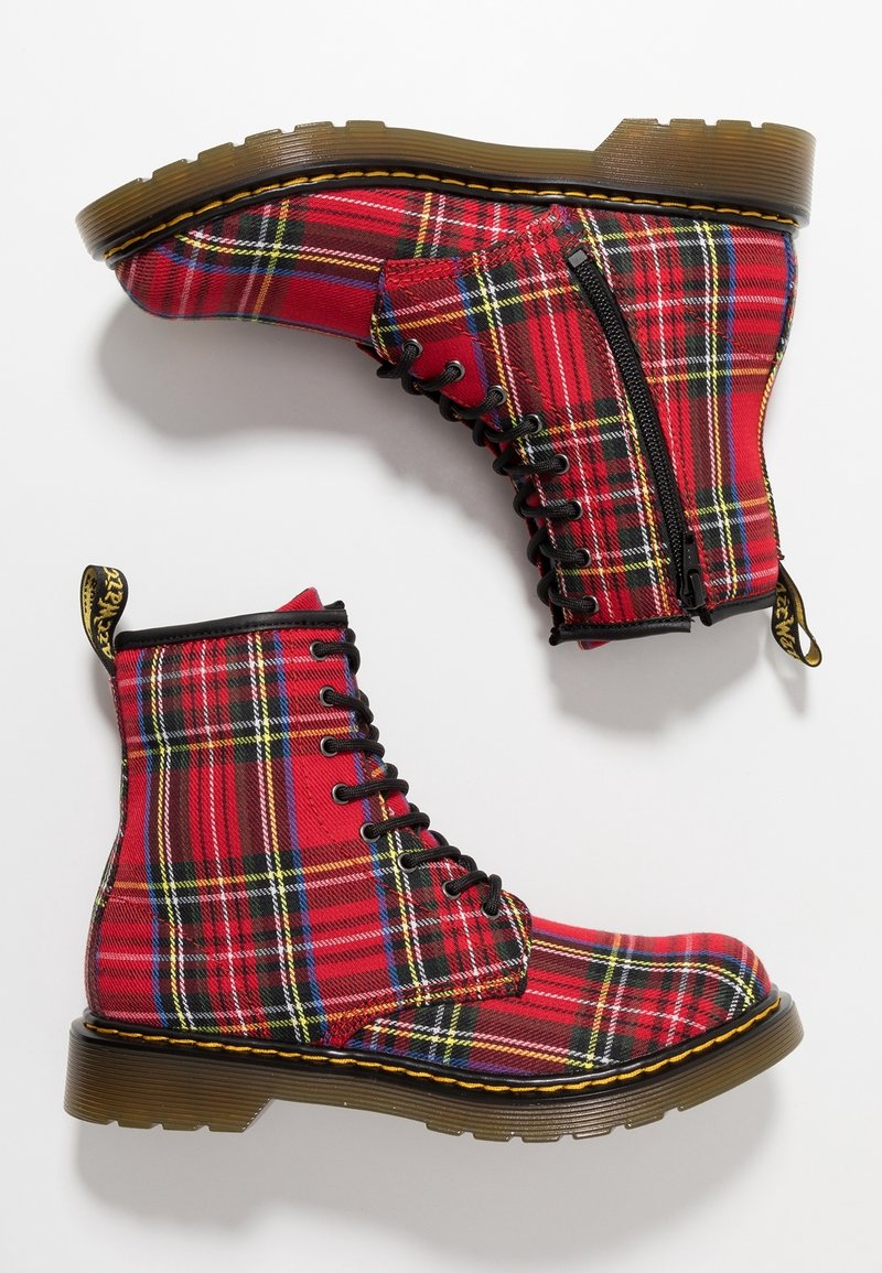 Paire de bottes à lacets à carreaux rouges avec fermetures éclair latérales et semelles épaisses translucides marron, montrées de côté et par dessous sur fond blanc.