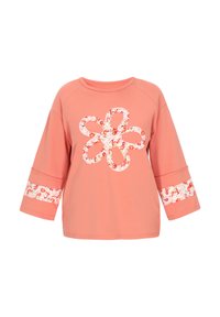Korallfärgad l�ångärmad topp med vida ärmar, med en stor blommig loopdesign på bröstet och blommiga band nära muddarna.