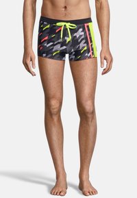 Shorts de bain pour hommes avec un motif géométrique dans des tons de gris, noir et des accents vifs en jaune fluo et rouge. Taille avec cordon de serrage.