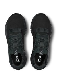 Een paar zwarte On Cloudnova sneakers met een geperforeerde tong, elastische band, veters en een gevoerde zool, van bovenaf bekeken op een witte achtergrond.