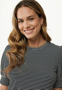 Maglietta a righe bianche e nere con maniche corte, scollatura rotonda, tessuto morbido e design fluido. Una collana dorata completa il look.