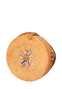 Borsa rotonda intrecciata in paglia con tracolla in pelle beige. Presenta un accento decorativo floreale realizzato con conchiglie e perline sul davanti.