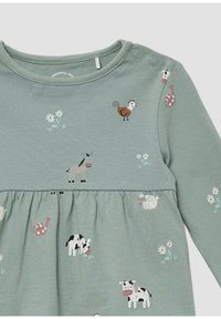 Zielona sukienka z długim rękawem, ozdobiona wzorami zwierzęcymi i roślinnymi, z falbaną u dołu i zatrzaskami na ramieniu ułatwiającymi zakładanie.