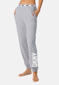 Grijze joggers gemaakt van zachte stof met een elastische tailleband met het zwarte "DKNY" logo. Inclusief zijzakken en elastische boorden bij de enkels.