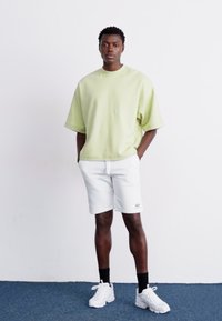 Limegrøn oversized kortærmet sweatshirt kombineret med hvide shorts og hvide sneakers. Simpelt design med en afslappet pasform.