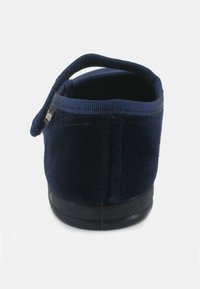 Pantofola in velluto blu navy con una texture morbida e un manico ad anello sul retro. Dotata di una suola in gomma per una buona aderenza e durata.