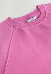 Sweatshirt roz cu un guler rotund ribat și detalii cusute. Fabricat dintr-un material moale, cu o textură netedă și un design casual.