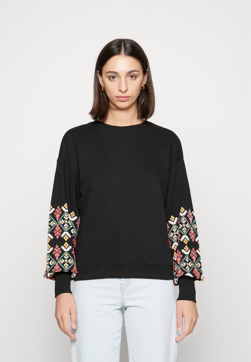 Sweatshirt preto com bordados geométricos coloridos nas mangas, gola redonda e punhos canelados. Material de algodão macio, corte relaxado.
