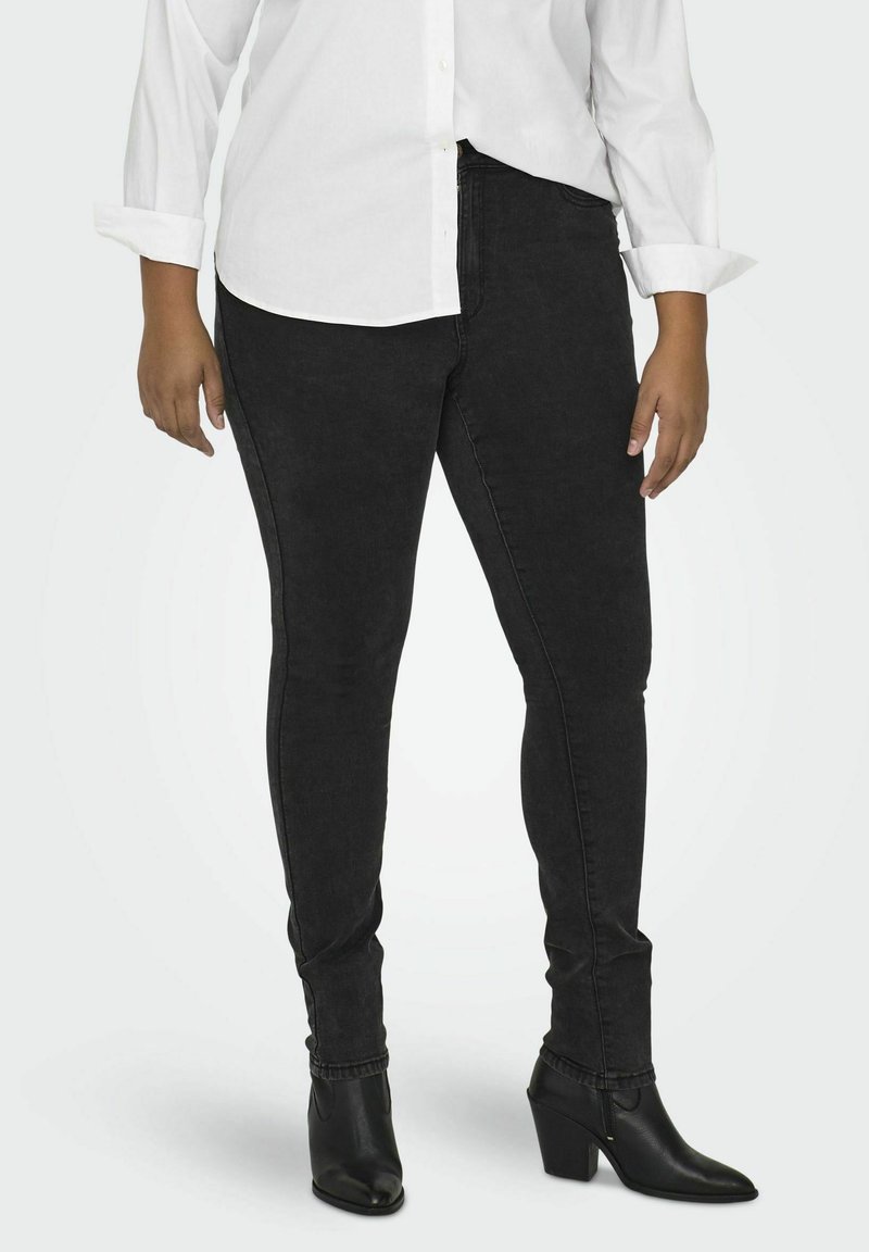 Black skinny jeans made from denim, featuring a high waist, subtle texture, and slim fit, paired with black heeled ankle boots.
