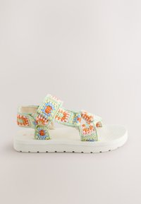 Sandales au crochet avec une base vert menthe et des accents multicolores en orange, bleu et jaune. Semelle texturée pour adhérence et confort.