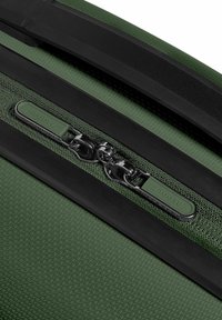 Groene gestructureerde bagage met zwarte accenten, voorzien van een ritssluiting en een trekhaak met het etiket "REDOLZ." Duurzaam materiaal met een gemusterde oppervlakte.