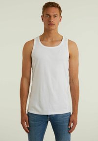 Tricou alb din bumbac, fără mâneci, cu decolteu rotund și un mic logo. Purtați-l cu blugi albaștri, având un design ajustat.