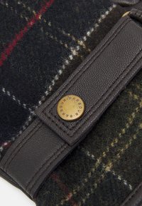 Plaid wool fabric in dark tones with red and white accents, features a brown leather strap with a metal button engraved "Barbour."