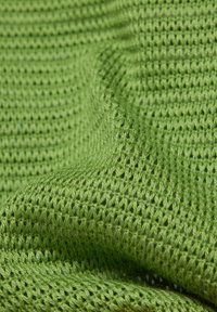 Grüner gestrickter Stoff mit einem strukturierten, offenen Webmuster. Das Material ist weich und flexibel, zeigt eine glatte Oberfläche und eine einheitliche Farbe.