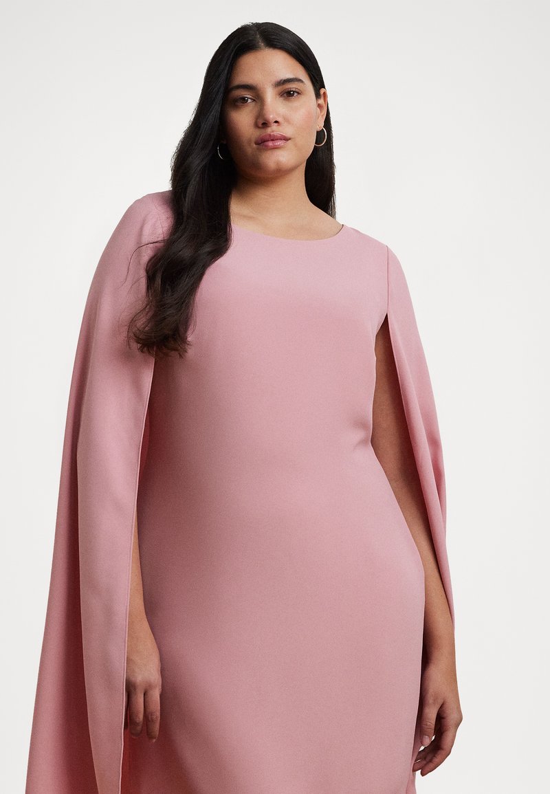 Vestido rosa con una textura suave, silueta ajustada y detalle de capa en los hombros. Presenta un escote redondo y diseño sin mangas.