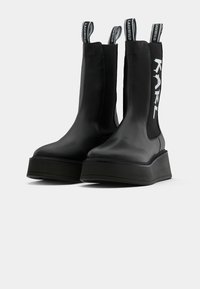 Bottes Chelsea noires à plateforme avec des côtés élastiques, des tirettes imprimées "LAGERFELD" et du texte blanc "KARL" sur les tiges extérieures.
