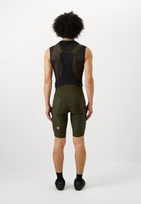 Fietsoutfit voor heren met een zwarte mesh bovenkant en olijfgroene shorts, met een nauwsluitende pasvorm en een zichtbaar logo op de linker dij.