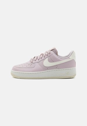 Sneaker in pelle rosa chiaro con dettagli bianchi, lacci piatti, punta perforata e suola in gomma testurizzata con il logo "AIR" sul tallone.