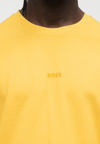 Κίτρινη κοντομάνικη μπλούζα, μαλακό βαμβακερό ύφασμα, διαθέτει ανάγλυφο τόνο λογότυπο "BOSS" στο στήθος, στρογγυλή λαιμόκοψη και άνετη εφαρμογή.