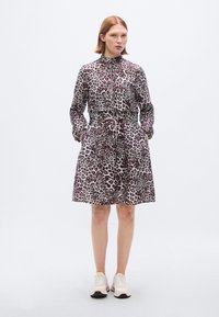 Φόρεμα με λεοπάρ σχέδιο, υψηλός γιακάς, φερμουάρ μπροστά και ζώνη στη μέση. Κατασκευασμένο από υφή ύφασμα, διαθέτει δύο πλαϊνές τσέπες και μακριά μανίκια.