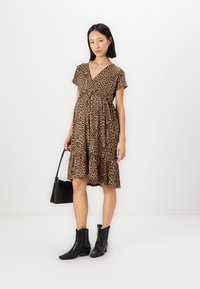 Leopard print dress with short sleeves, v-neckline, gathered waist, and tiered hem. Paired with black ankle boots and a small black bag.