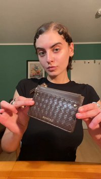 Καφέ, υφασμένο δερμάτινο πορτοφόλι καρτών με φερμουάρ, featuring λογότυπο ενσωματωμένο στο κάτω μέρος και μεταλλικές λεπτομέρειες.