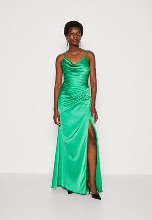 Green satin evening dress with a cowl neckline, ruched sides, and a thigh-high slit. Features thin straps and a smooth texture.