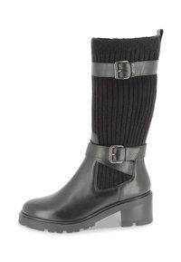 Bota de tobillo de cuero negro con caña de punto acanalado. Presenta un detalle de correa y hebilla, punta redonda y tacón bajo apilado.