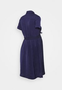 Mörkblå klänning med krage och korta ärmar. Har en åtsittande midja med ett tygbälte och en slät textur.