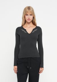 Maglietta nera a maniche lunghe con scollo a V e motivi decorativi di ali argentate sulle spalle. Tessuto morbido, silhouette aderente.