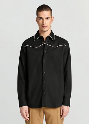 Chemise noire boutonnée avec un piping blanc contrastant le long du col et de la poitrine. Fabriquée dans un tissu lisse, elle a des manches longues et une coupe régulière.