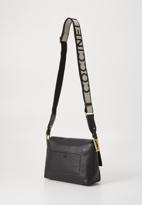 Sac en cuir noir à bandoulière avec un design structuré, une finition texturée et une sangle ajustable ornée d'un logo. Il dispose d'une poche frontale élégante.
