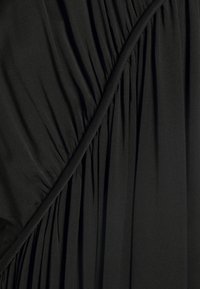 Tissu noir pour robe avec des plis horizontaux et une texture lisse. Présente une couture angulaire avec un drapé pour plus de dimension.