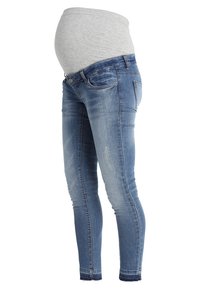 Gravid överkropp med grå topp och blå gravidjeans med elastisk midja och blekt tvätt på vit bakgrund.